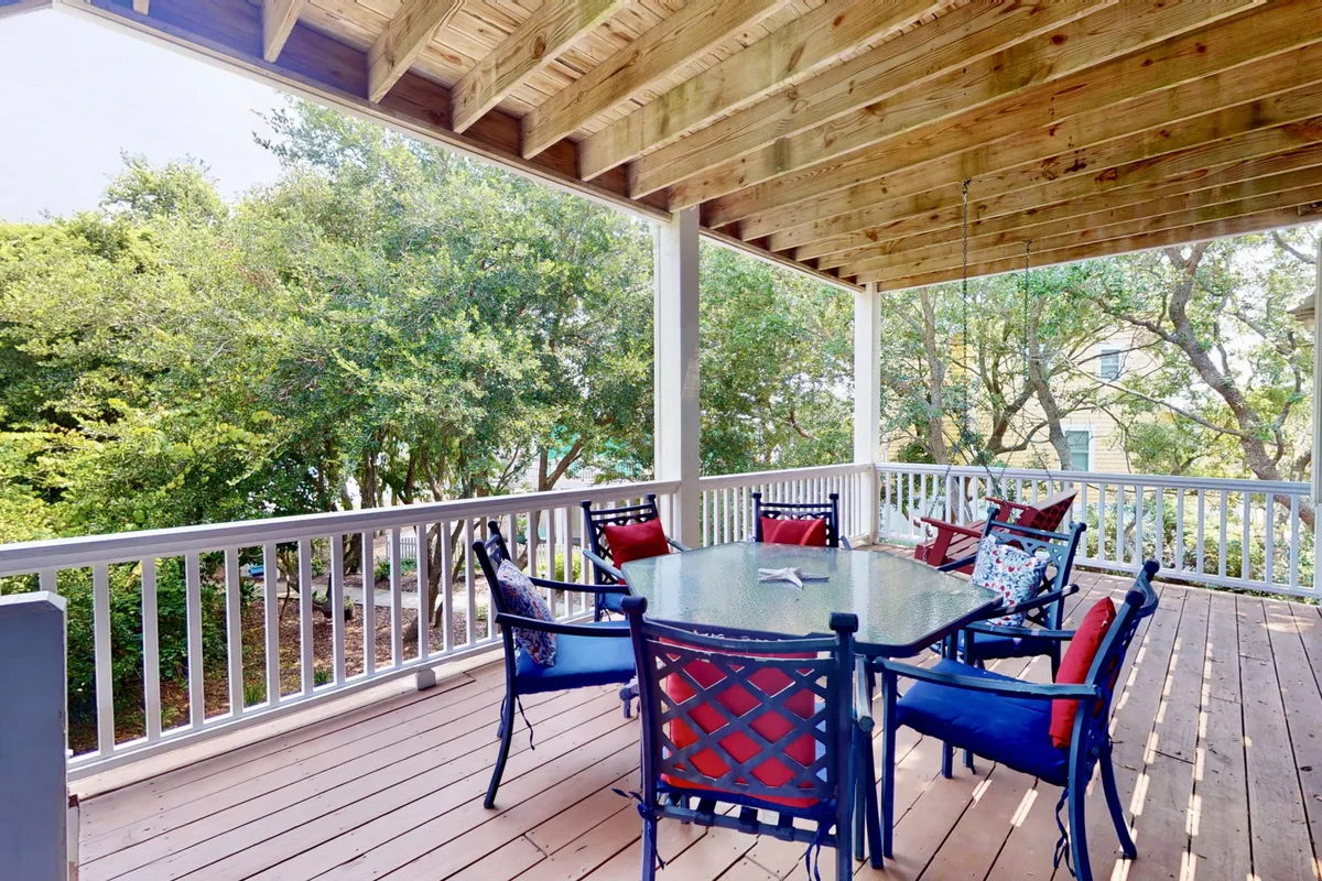 A cheerful exterior scene featuring a spacious outdoor dining table with colorful cushions, surrounded by lush greenery. The setting feels inviting, perfect for group meals, social gatherings, and relaxing in the fresh air, with hints of sunset light enhancing the atmosphere.