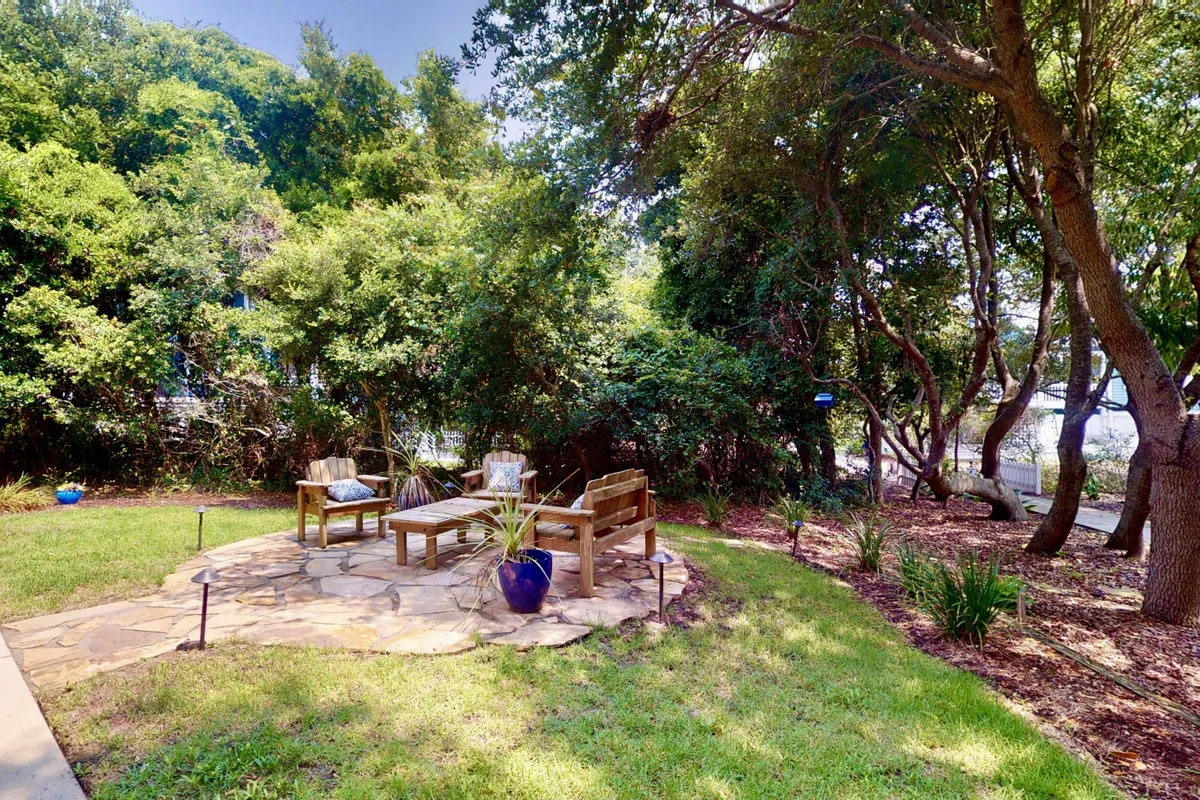 A peaceful stone patio with wooden seating and lush greenery surrounding the area. The setting invites relaxation, socializing, or quiet moments outdoors—an ideal spot for pets and their owners to unwind after a day of adventure.