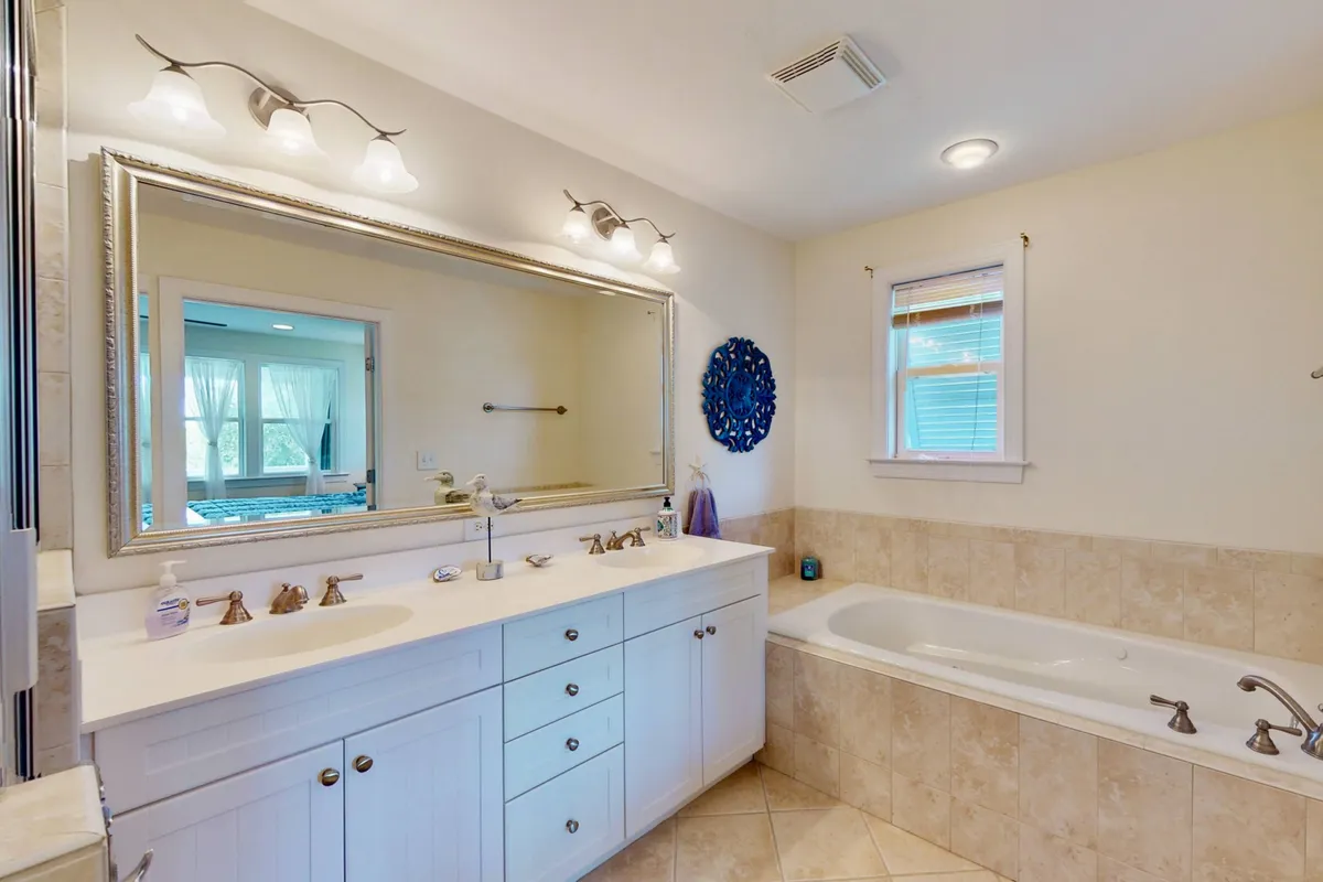 A serene bathroom with a freestanding tub, double sink vanity, and large mirror, all set in a calming color palette. Decorative wall art and thoughtful details evoke a spa-like atmosphere perfect for relaxation and self-care.